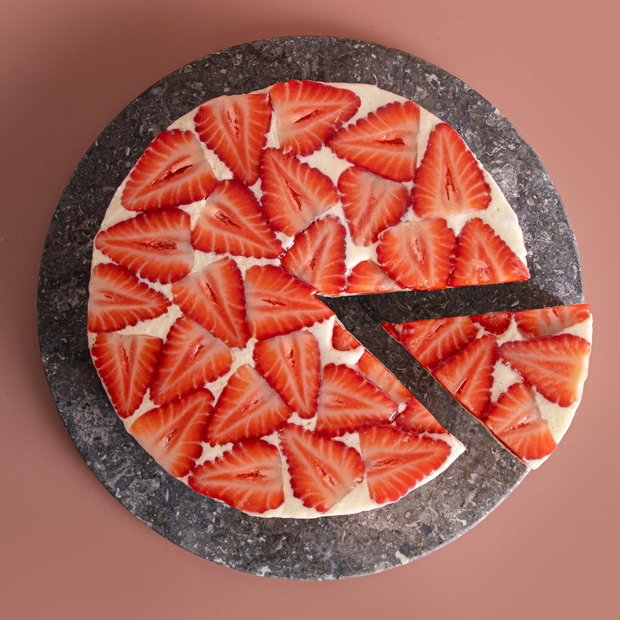 A sliced strawberry cake with a light sponge and cream layers, presented on a plate.